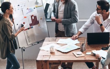 collaborateurs en présentation dans une entreprise autour d’une table avec un tableau blanc