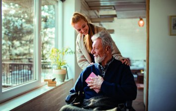 senior en situation de handicap, utilisant un fauteuil roulant et bénéficiant d’une assistance humaine