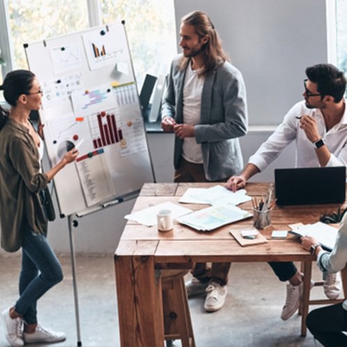 collaborateurs en présentation dans une entreprise autour d’une table avec un tableau blanc