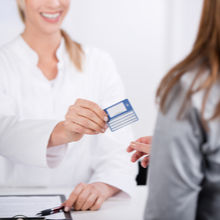 jeune médecin souriante donnant une carte de tiers payant ou carte mutuelle à un patient