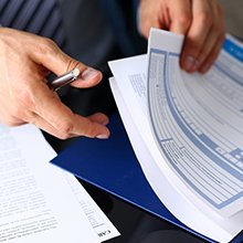 bras masculin en costume tient un formulaire d'assurance découpé en pavé avec un stylo